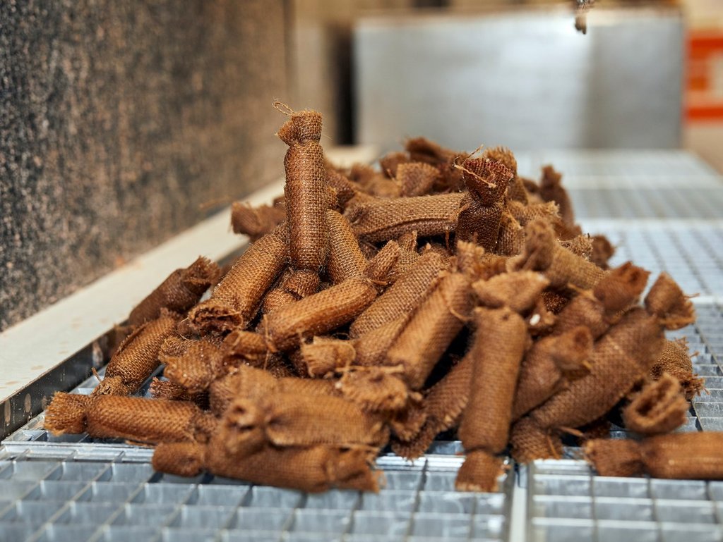 Ein Haufen kleiner, brauner Säckchen aus grobem Stoff liegt auf einem Metallgitter.