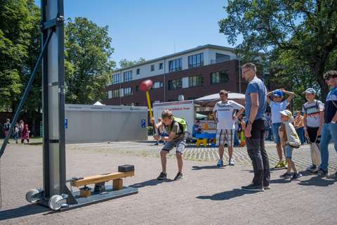 Eine Person schlägt mit einem Hammer auf eine Vorrichtung, während mehrere Personen zuschauen.