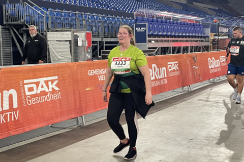 Eine Person mit Startnummer läuft in einer Halle an einer Absperrung entlang.
