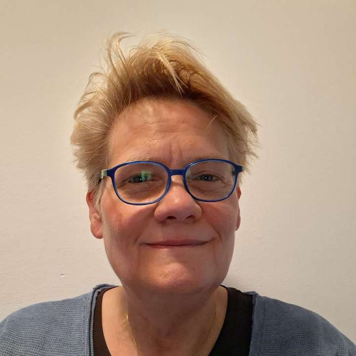 Eine Person mit kurzem, hellbraunem Haar und blauen Augen blickt direkt in die Kamera.