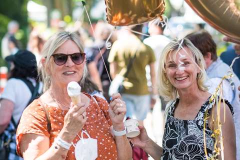 Zwei Personen halten Eis und Luftballons, eine davon trägt eine Sonnenbrille.