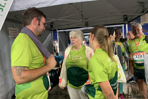 Mehrere Personen in grünen Sportshirts stehen unter einem Pavillon und unterhalten sich.