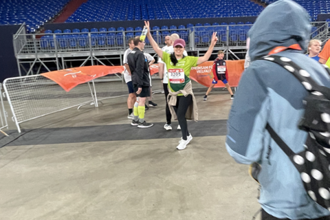 Eine Person mit Startnummer hebt die Arme, während mehrere Personen in Sportkleidung in einer Halle stehen.