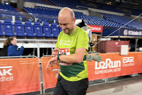 Eine Person in Sportkleidung läuft in einer Halle und schaut auf eine Uhr am Handgelenk.