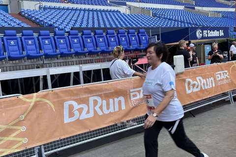 Eine Person geht an einer Absperrung mit B2Run-Banner in einem Stadion vorbei.