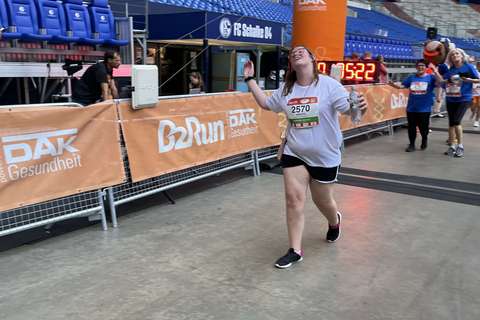 Eine Person läuft durch einen orangefarbenen Zielbogen in einem Stadion.