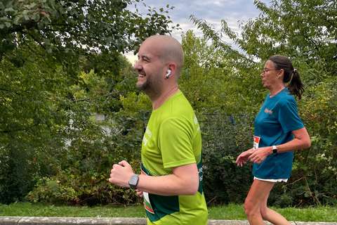Zwei Personen joggen nebeneinander im Freien vor grünem Gebüsch.