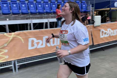 Eine Person mit Startnummer läuft in einem Stadion und hält eine Wasserflasche in der Hand.