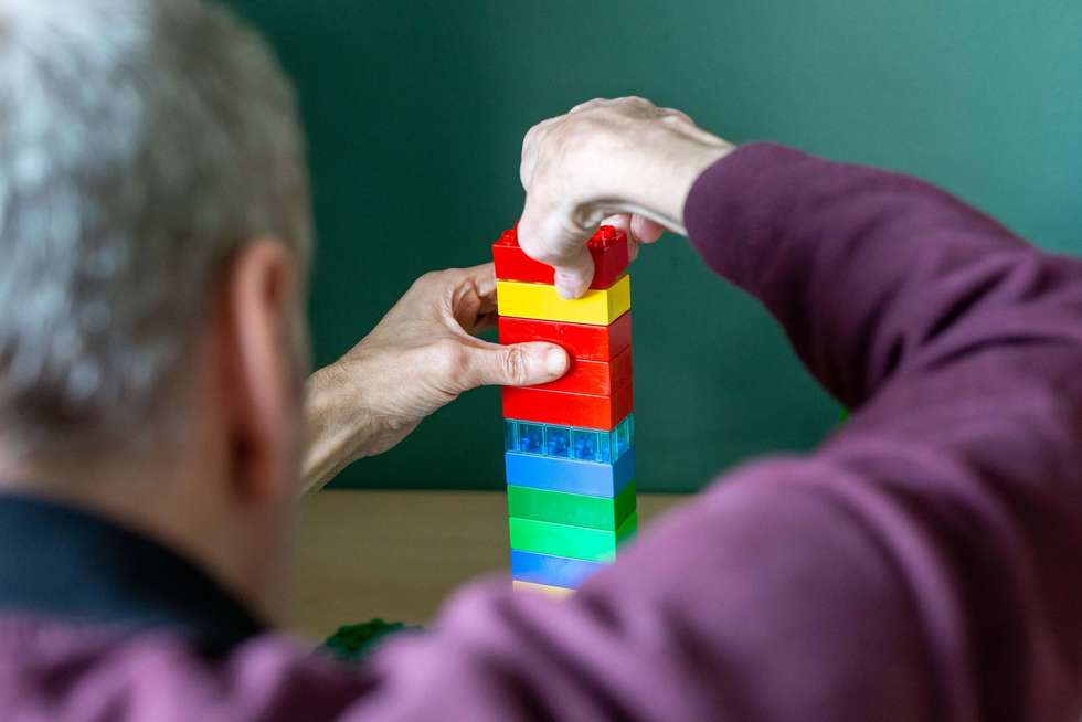 Eine Person stapelt bunte Bausteine zu einem Turm.